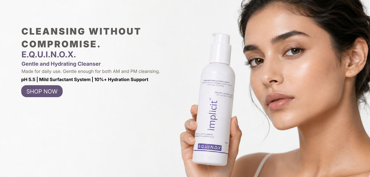 Hand holding an implicit E.Q.U.I.N.O.X. gentle face and body cleanser pump bottle against a soft lavender background.