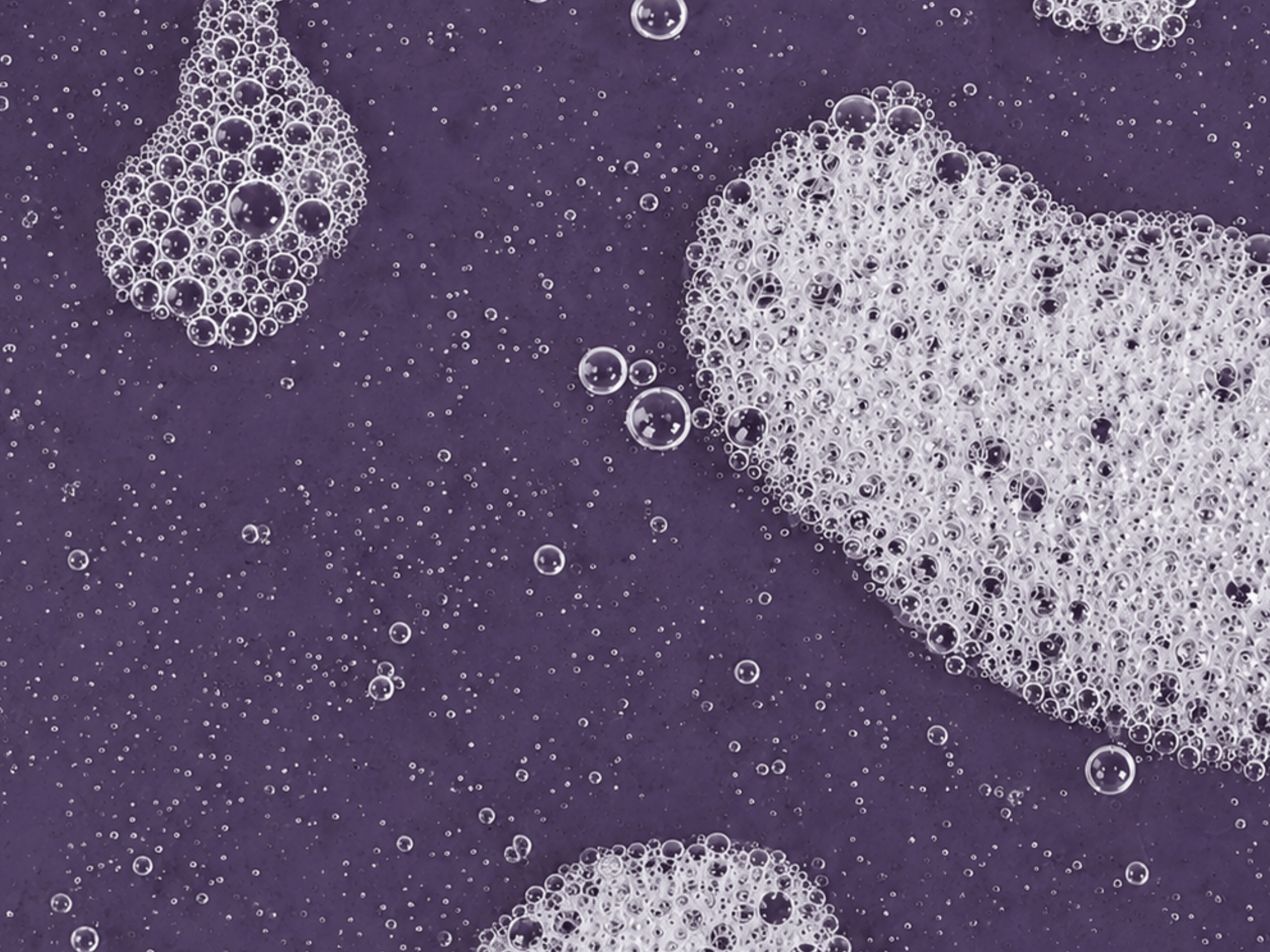 Close-up of the soft foaming texture of Brand Implicit E.Q.U.I.N.O.X. gentle hydrating cleanser on a purple background.