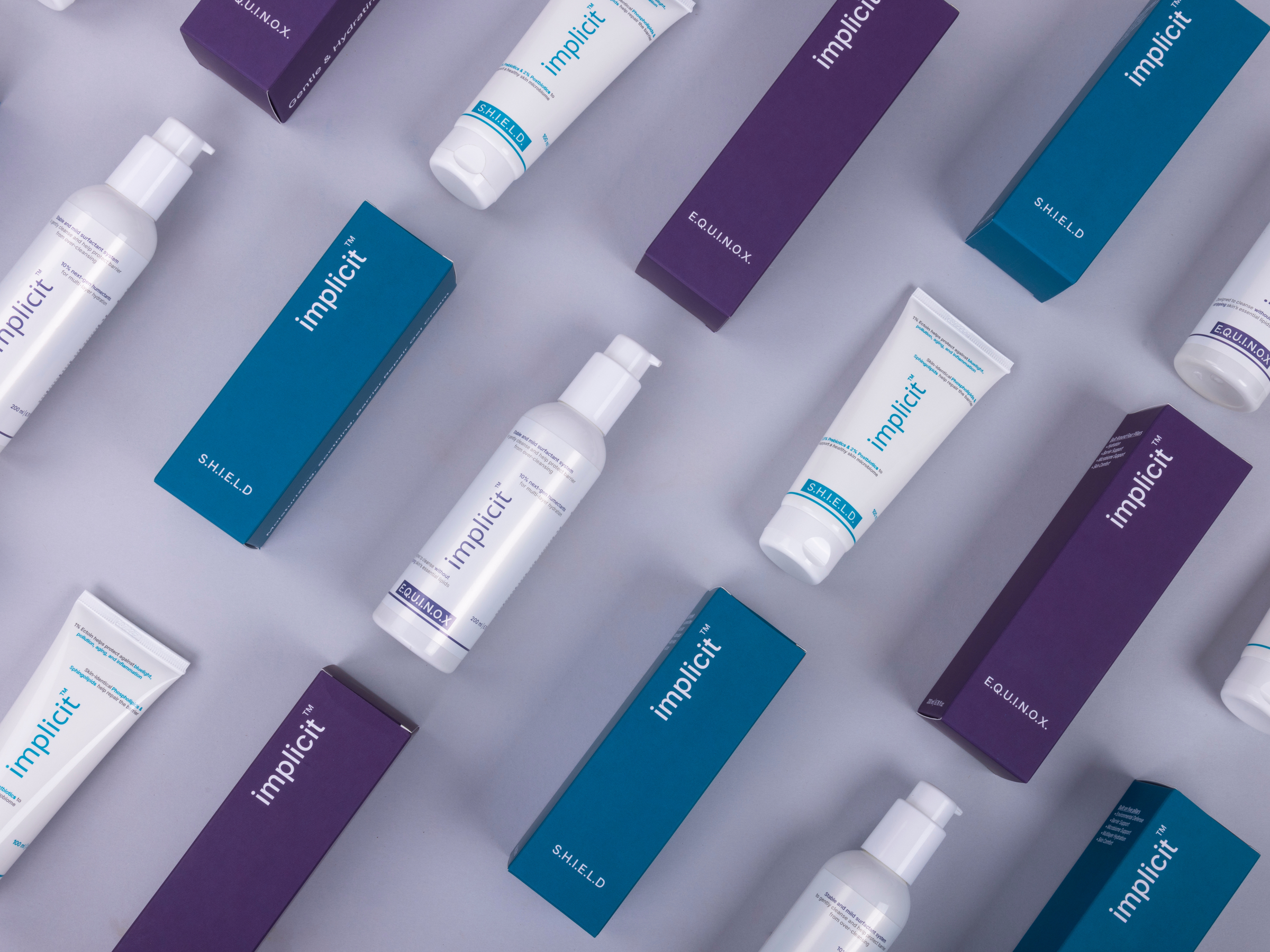 Brand implicit E.Q.U.I.N.O.X. cleanser and S.H.I.E.L.D. barrier repair gel cream arranged with their purple and teal packaging.